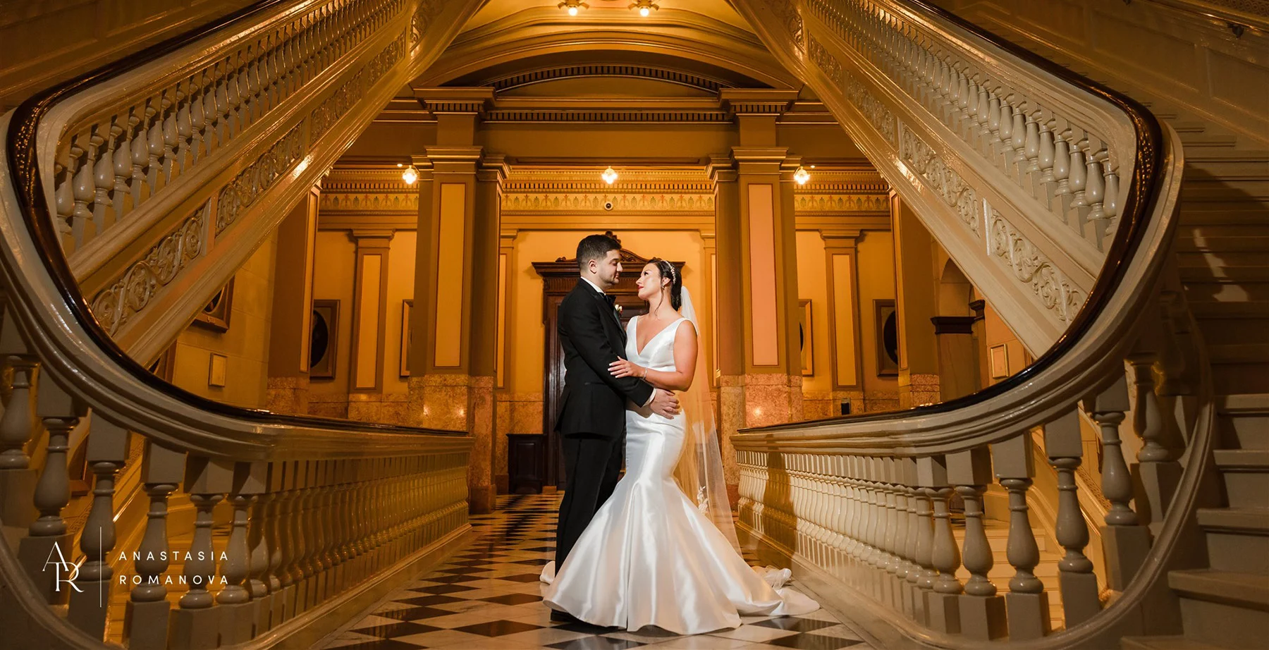 Bride and groom in hallway surrounded by ornate staircases