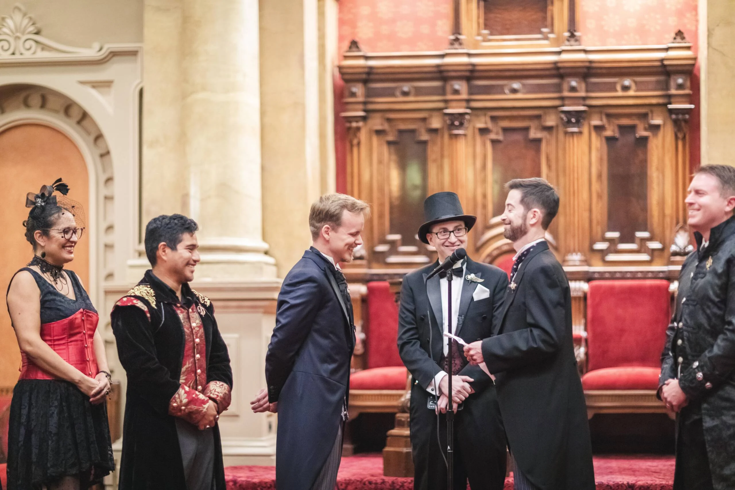 DanielKutinskyCeremony-177-scaled Grooms exchanging vows surrounded by party in black and red