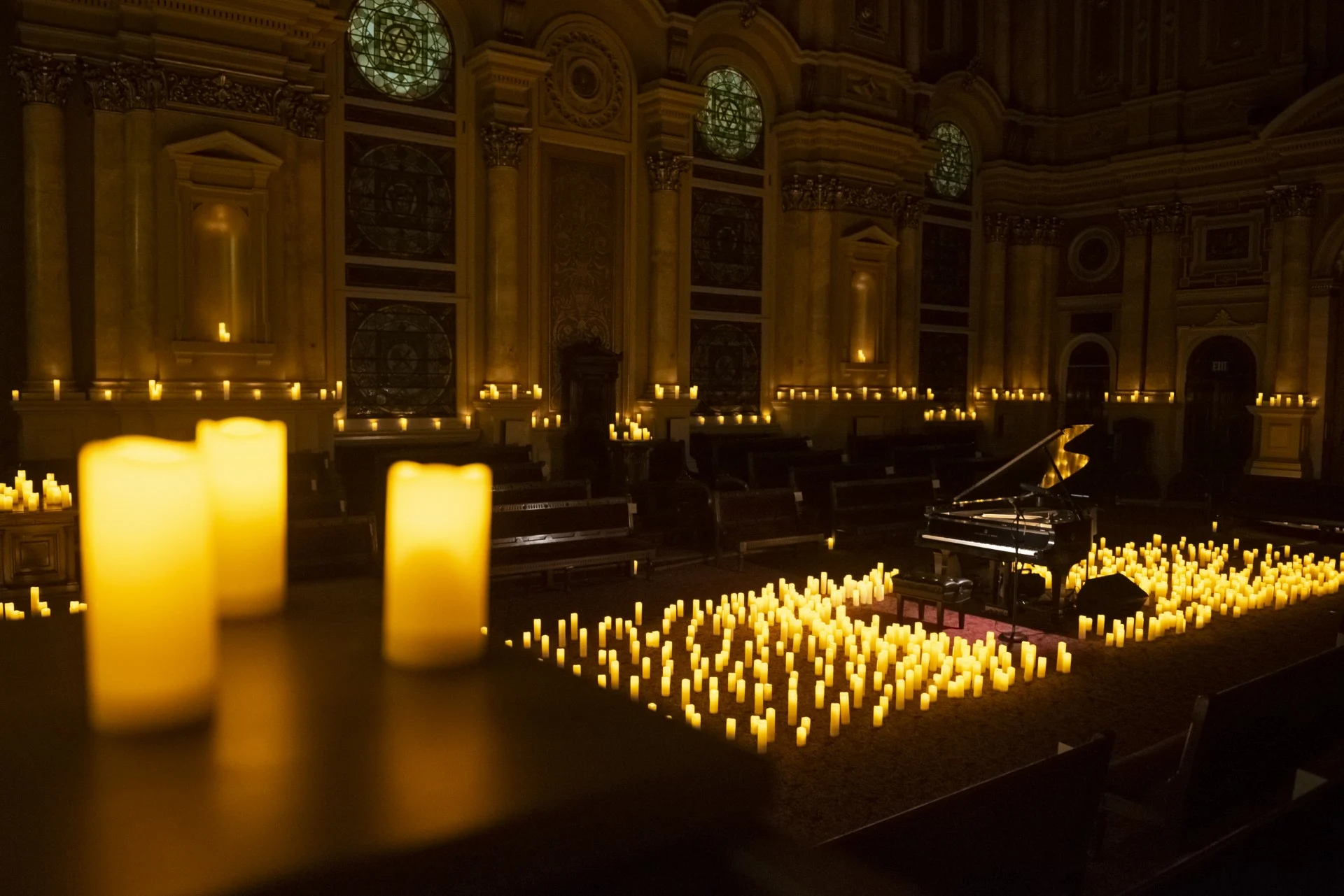 Wide photo of room with piano in the center with candles surrounding it