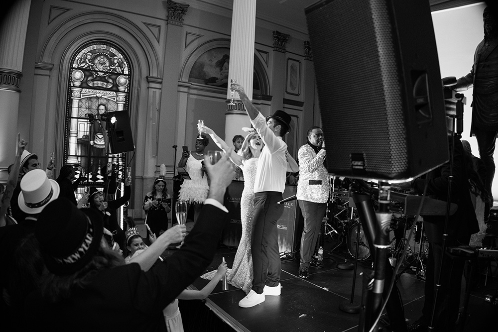 12_31_24_J_M_Wedding_-1991 (1)sm Couple posed pm stage in front of crowd.