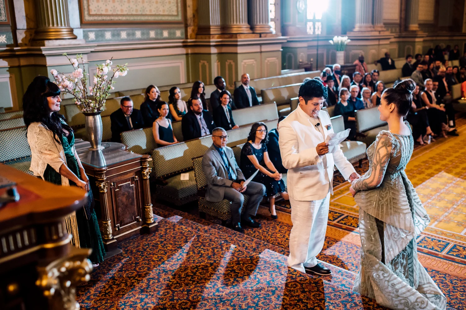 0290 Couple reading their vowels while guests are seated on benches in the background.