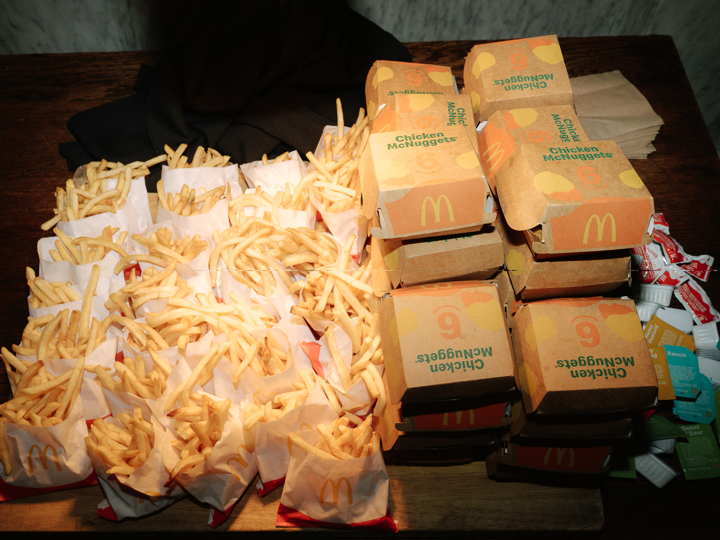 McDonalds chicken nuggets, french fries and dipping sauces laid out on table.