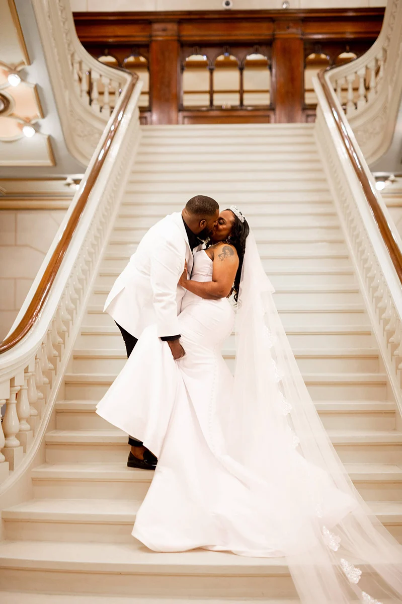 Classic-Photographers-scaled Bride and groom kissing on marble staircase.