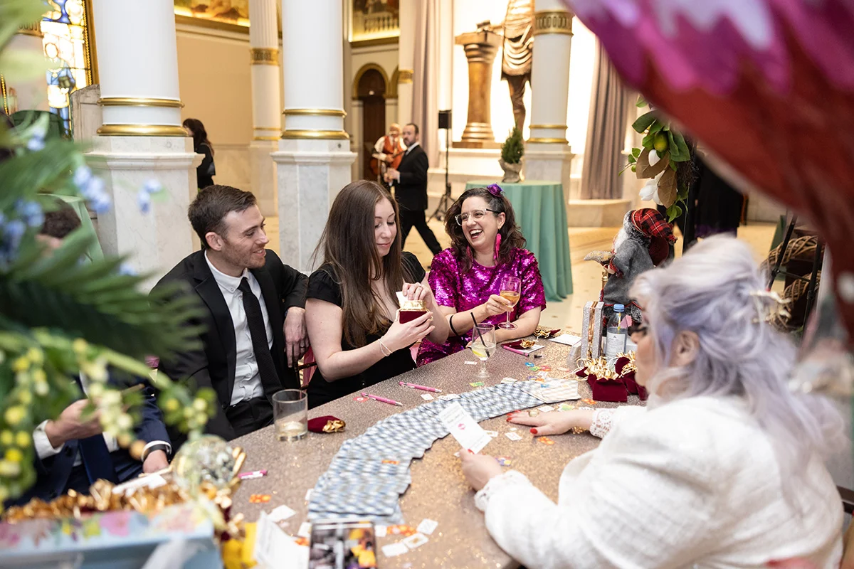 Eddie Marenco Photography (2) Smiling group in formal attire seated at table while woman in front of them has cards spread in front of her.