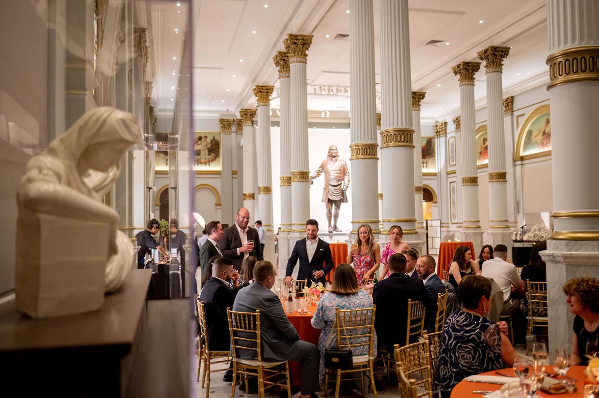 Ginger Fox Photography Guests in formal attire seated at large, round tables in ballroom. Sculptures are to the side and back of the room.