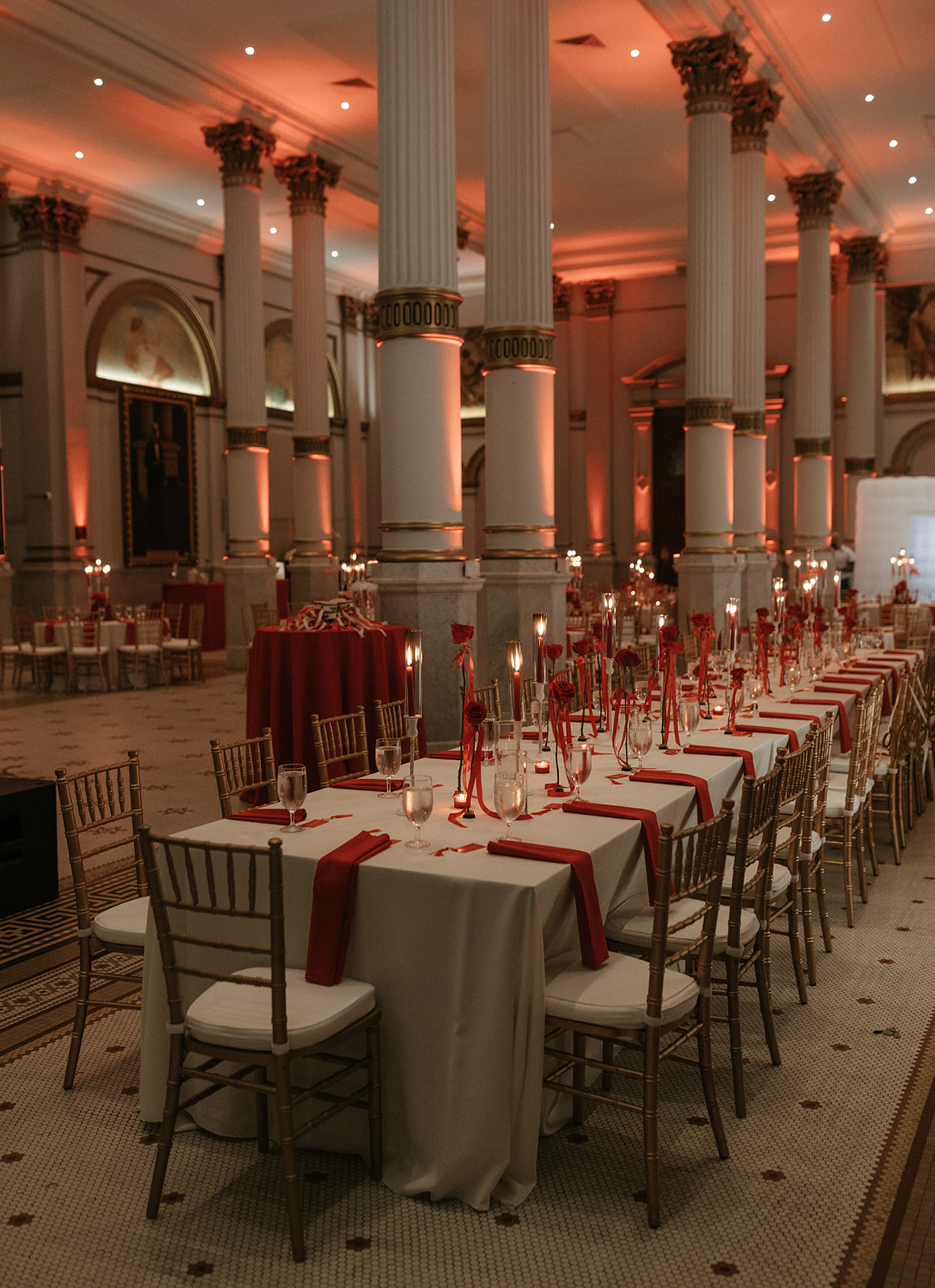 Red-lit room with large table with white table cloth and red napkins.