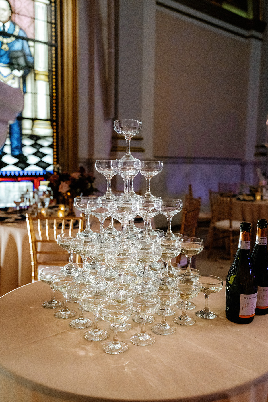 Tower of champagne glasses with bottles next to it.