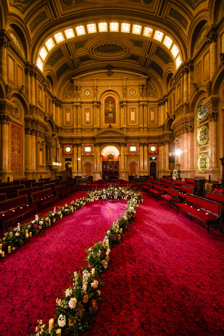 Section 9 Photo 1 Hall with high ceiling and ornate walls with flowers laid out in an aisle down the center.