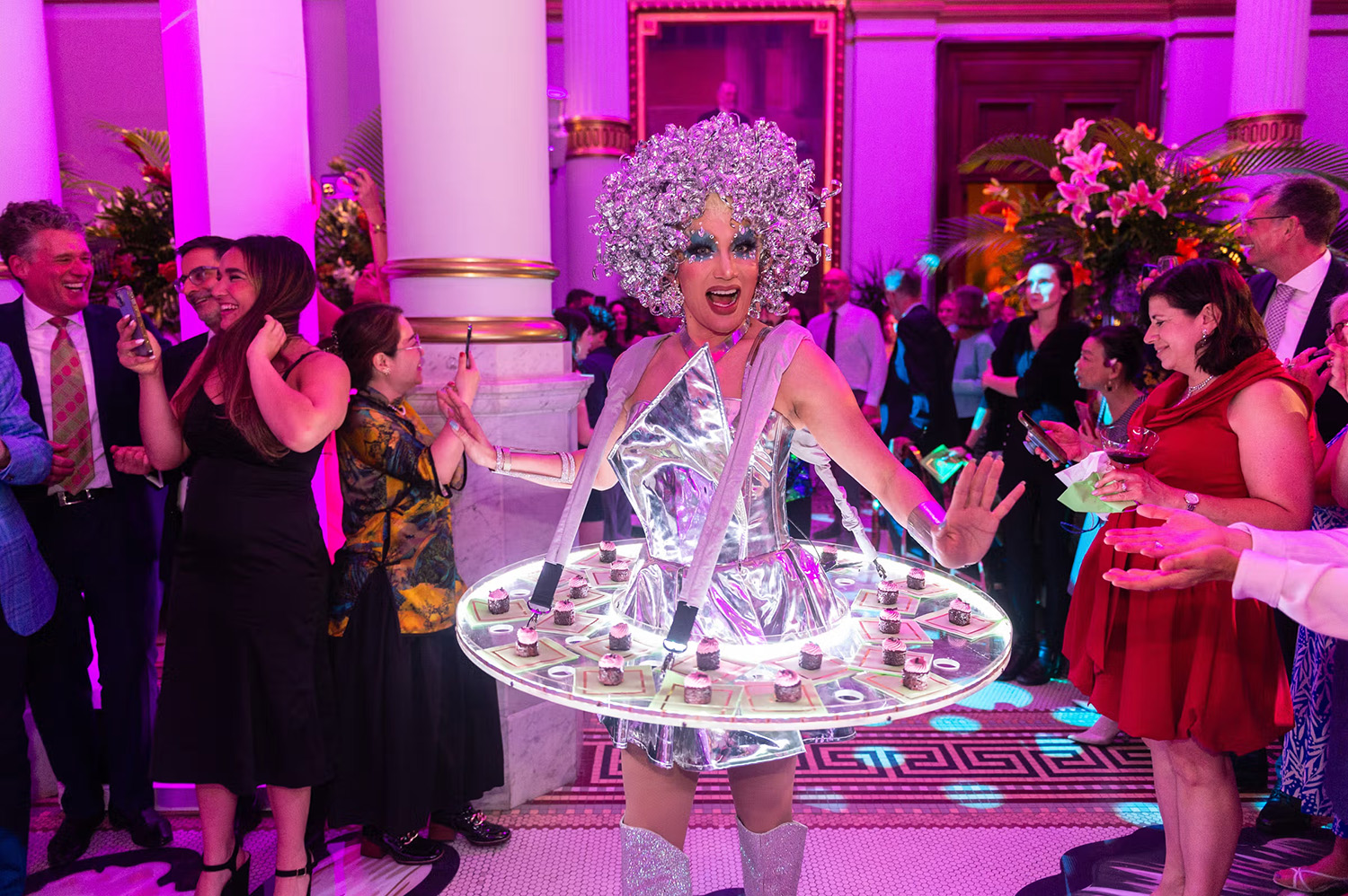 Smiling woman in silver outfit with small appetizers set on her skirt