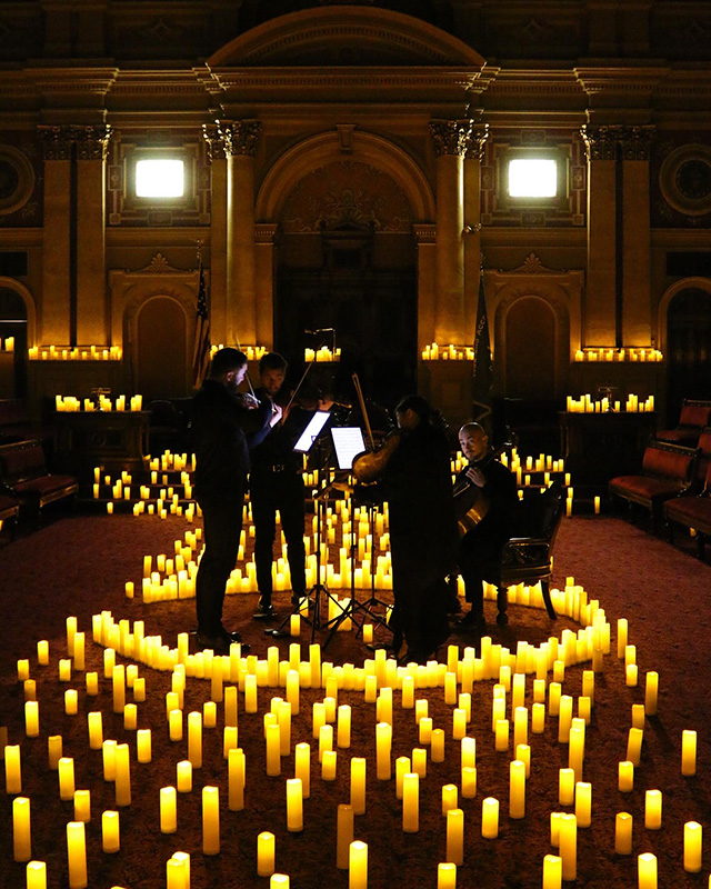 2022-11-09 12.36.32-3 (1) Musicians playing in a large room surrounded by candlelight.